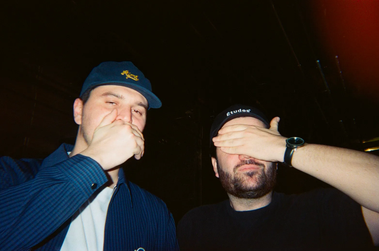 Carl et Noé côte à côte : l’un cache sa bouche et l’autre ses yeux avec une main.